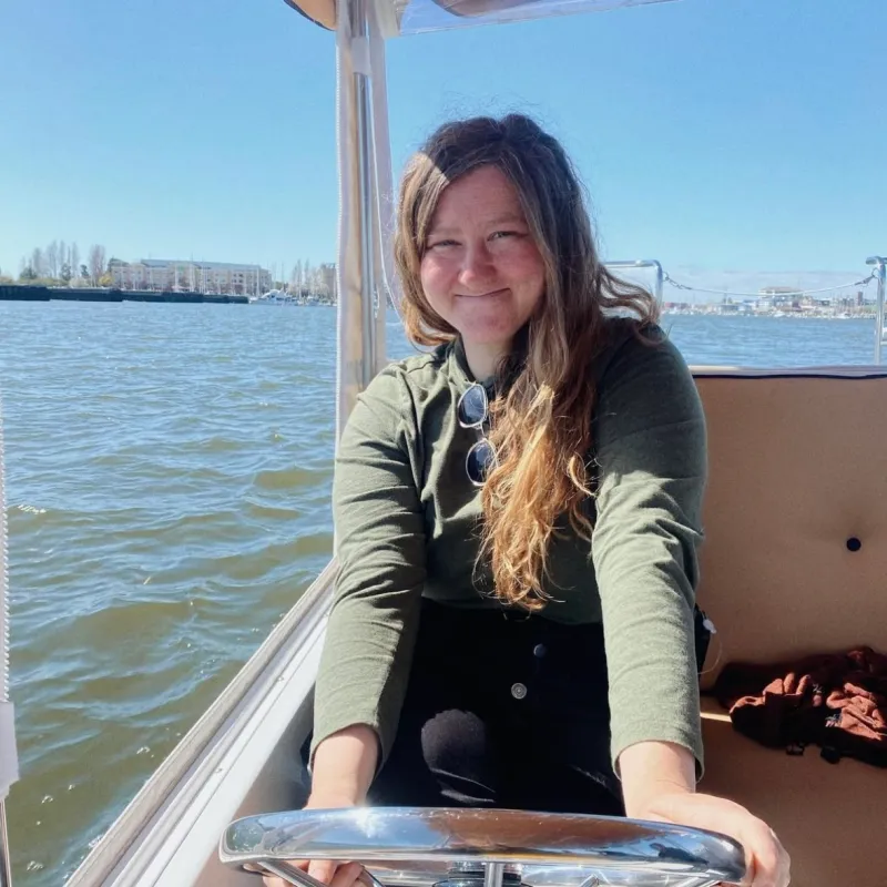 a woman sitting on a dock next to a body of water